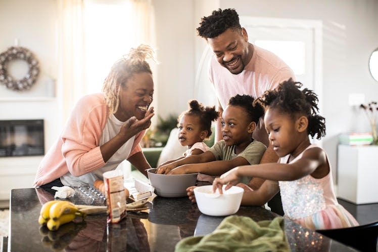 Mom, dad, and three kids mixing cookie dough in their kitchen at home.