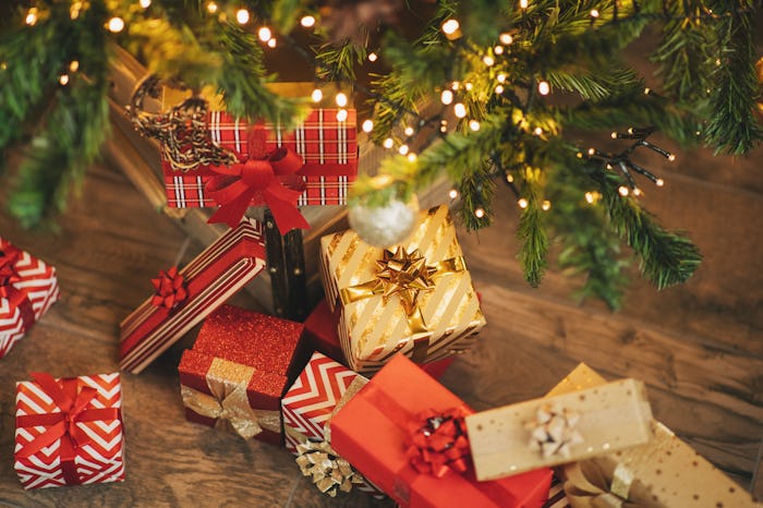 Beautiful Christmas gifts under fir tree on floor in room