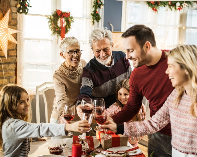Happy multi-generation family toasting while celebrating New Year in dining room.