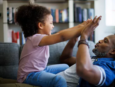 Happy father and his adorable little daughter having fun at home