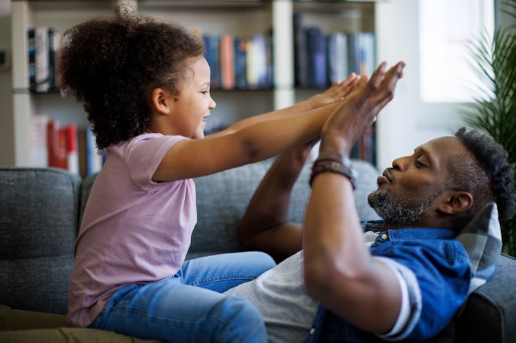 Happy father and his adorable little daughter having fun at home