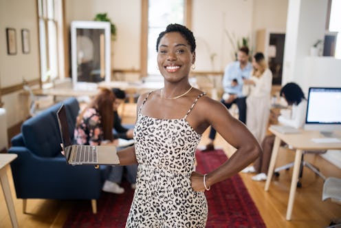 A portrait of a smiling African American business woman in a modern shared office creative collectiv...