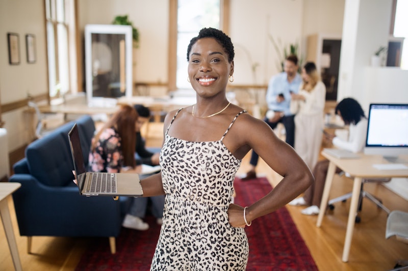 A portrait of a smiling African American business woman in a modern shared office creative collectiv...