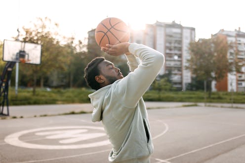 Young man practicing basketball alone at sports court in the morning