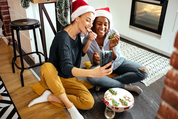 two women sitting on the floor enjoying holiday cookies, as they consider their Christmas 2023 horos...