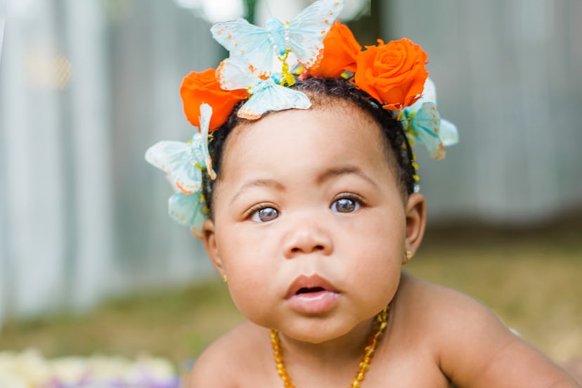 Baby girl with butterfly and flower crown, in Romper’s baby name trend predictions for 2024.