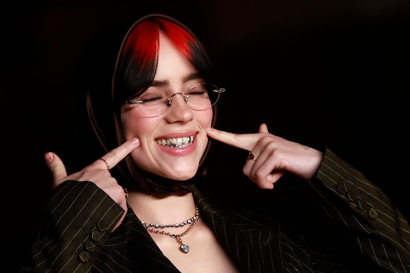 Billie Eilish wore a plunging low-cut matching pinstripe set with a headscarf & silver tooth gems at…