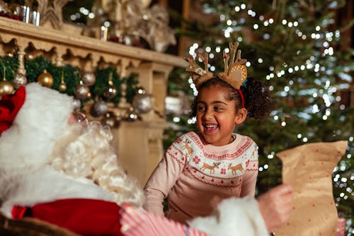 Girl visiting Santa at a Santas grotto in Newcastle Upon Tyne. Santa is reading a 'naughty or nice' ...