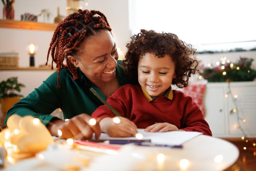 Mother and cute little son drawing together during christmas time, writing a thank you note for chri...