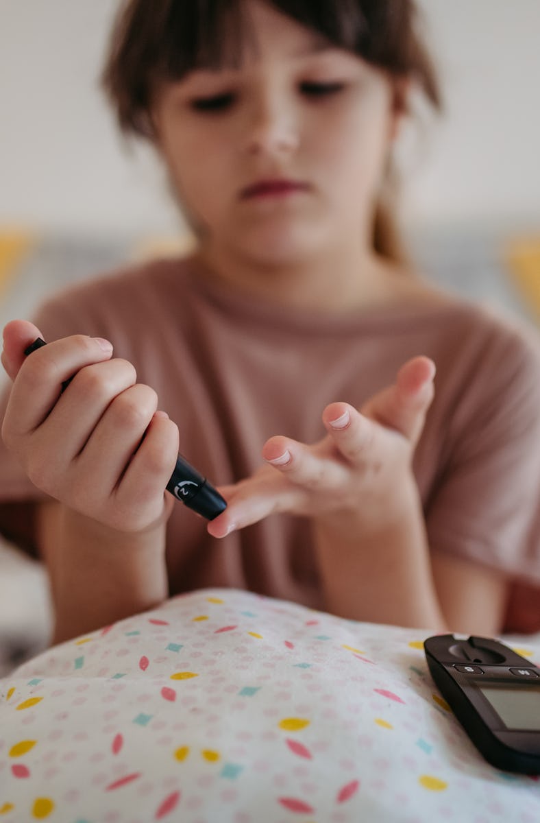 Girl collecting a blood sample from her finger. Diabetic girl taking finger stick test at home to ch...