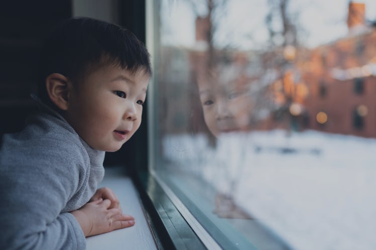 Boys looking out the window on a snowy day. The backyard glows with light