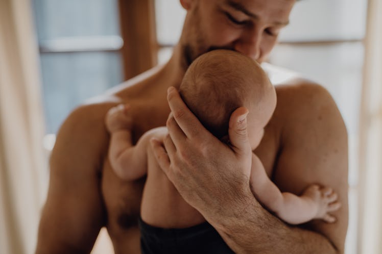 Cheerful father holding his cute newborn baby.
