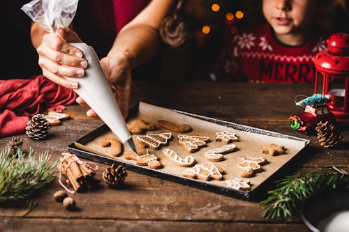 Woman decorating gingerbread cookie with a great icing recipe with her kid. 