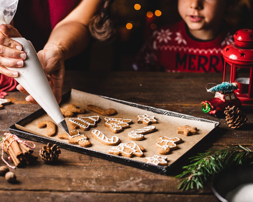 Woman decorating gingerbread cookie with a great icing recipe with her kid.