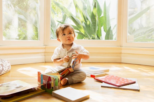 baby sitting in sunroom, looking at books in article listing boy names inspired by classic literatur...