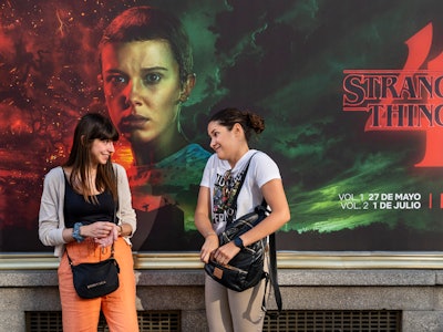 MADRID, SPAIN - 2022/05/27: Women talk in front of a street commercial advertisement banner from the...