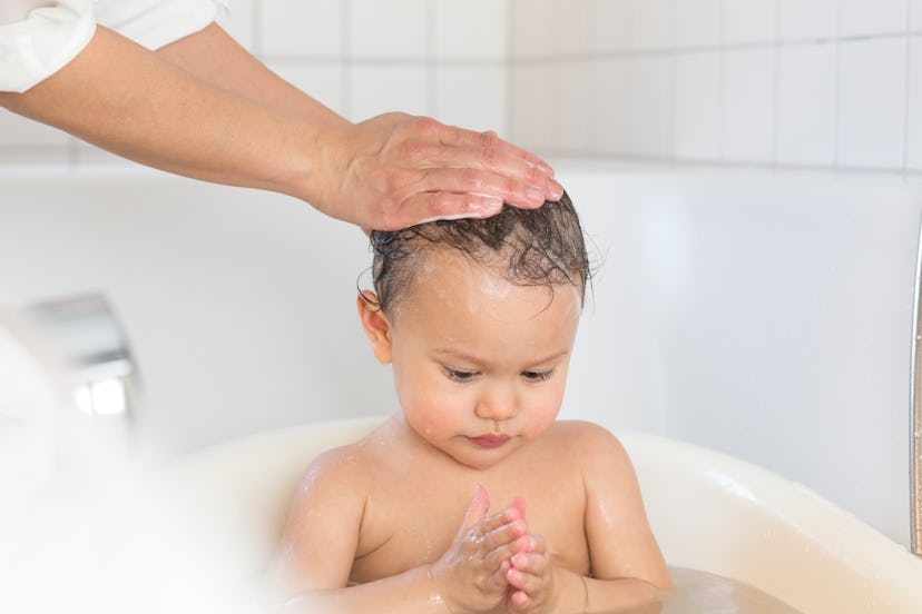 a baby in the tub getting cradle cap treatment because their parent wondered how to get rid of cradl...