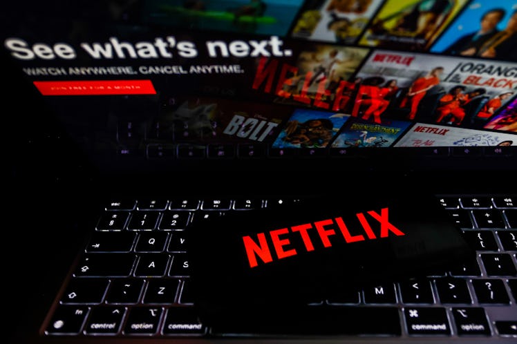 Netflix logo is displayed on a mobile phone screen with Netflix website in a background for illustra...