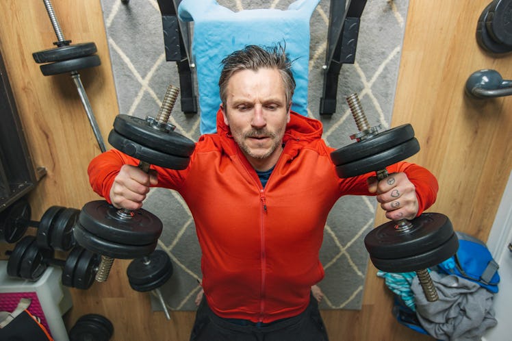 A man lifting dumbbells on a bench.