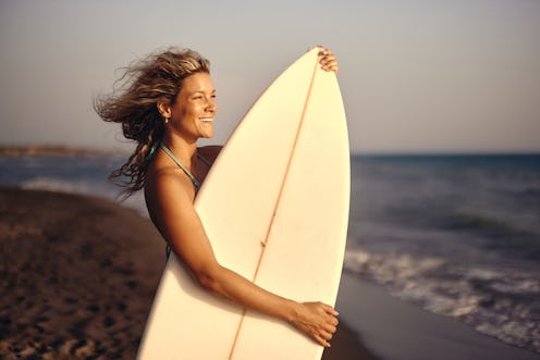 Young happy female surfer enjoying in summer day on the beach. Copy space.