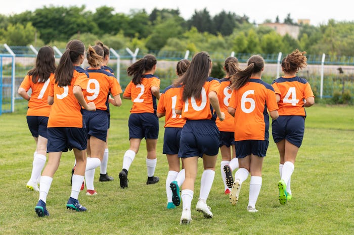 Female soccer players warming up on the field.