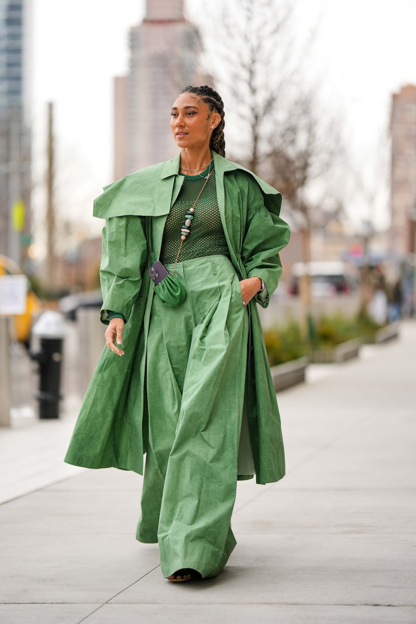 NEW YORK, NEW YORK - FEBRUARY 12: A guest wears diamonds earrings, gold chain necklaces, a green mes...