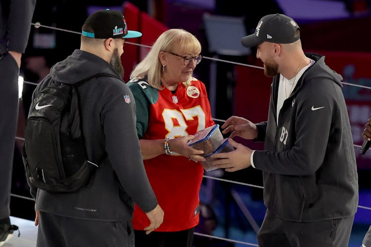 PHOENIX, ARIZONA - FEBRUARY 06: Mother Donna Kelce (C) gives cookies to her son's Jason Kelce (L) #6...