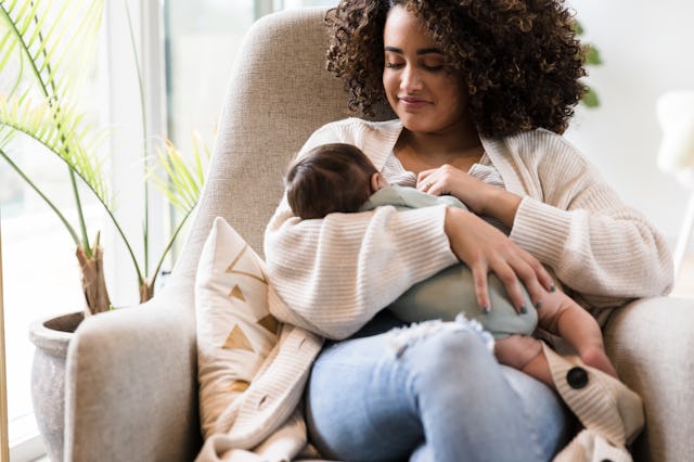 While sitting in a rocking chair, a first-time mom breastfeeds her baby boy.