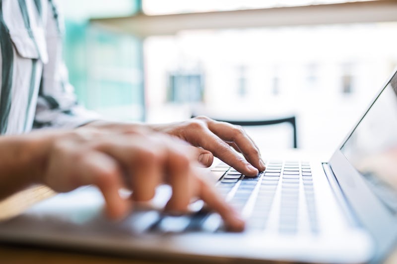 Unrecognizable person typing on her laptop in a cafe