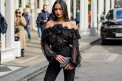 Kelsey Merritt wears black off shoulder ruffled top, black pants outside Carolina Herrera during New...