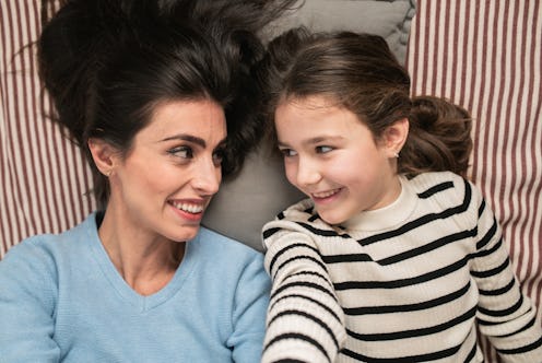 Portrait of the happy mother and daughter lying down on the floor and spending nice time together