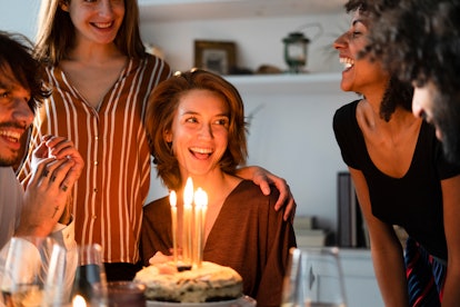 Friends celebrate a birthday with cake and candles, preparing to post photos with Pisces Instagram c...