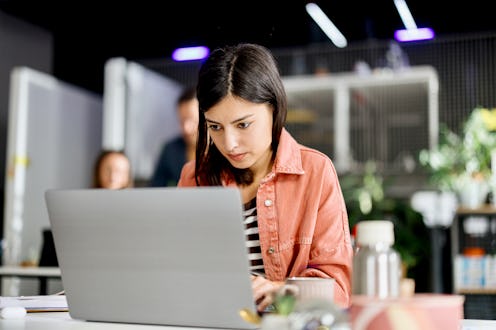 Beautiful young woman working in the modern office with her coworkers