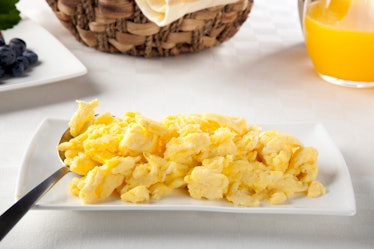 Scrambled eggs on white serving dish with serving spoon.