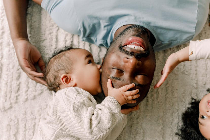 a father and baby snuggling on the floor, in an article about the 8 month sleep regression and how t...