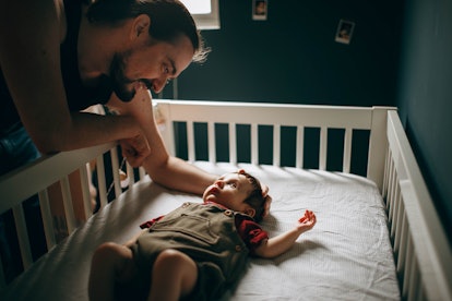 dad and baby in a crib in an article about the 6 month sleep regression