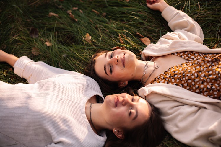 Two young women relax in a patch of grass as they consider the spiritual meaning of March 20, 2023, ...