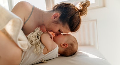 Mom and baby boy cuddling on the bed in the morning, in an article about the 8 month sleep regressio...