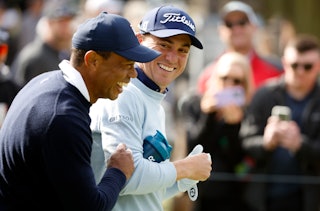 Tiger Woods of the United States and Justin Thomas of the United States walk across the ninth hole d...