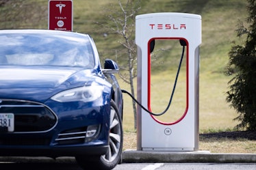 A Tesla Model S sedan is plugged into a Tesla Supercharger electrical vehicle charging station in Fa...