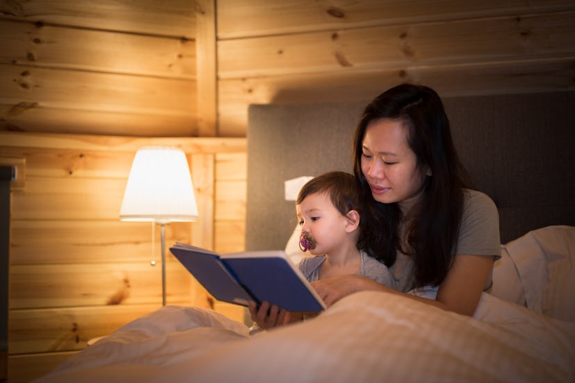 Mother reads a book to her daughter before bed time in an article about 12 month sleep regression