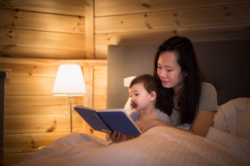 Mother reads a book to her daughter before bed time in an article about 12 month sleep regression