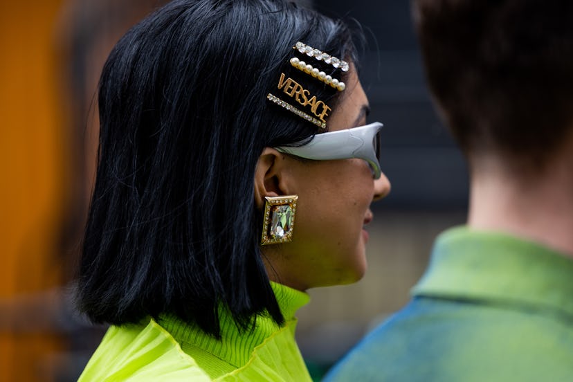 A guest wears Versace hair clip, sunglasses, earrings outside 16Arlington during London Fashion Week...