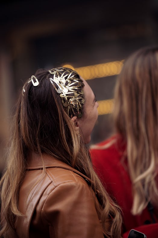 A guest wearing a brown leather coat and a lot of golden clips in the hair outside KWK by Kay Kwok f...