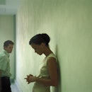 A woman leaning against a wall and a man in the distance whom she's giving the silent treatment