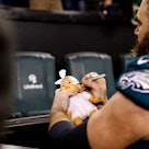 Jason Kelce #62 of the Philadelphia Eagles signs a baby doll for a fan after an NFL divisional round...