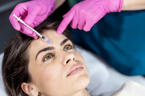 Young woman gets beauty facial injections in salon