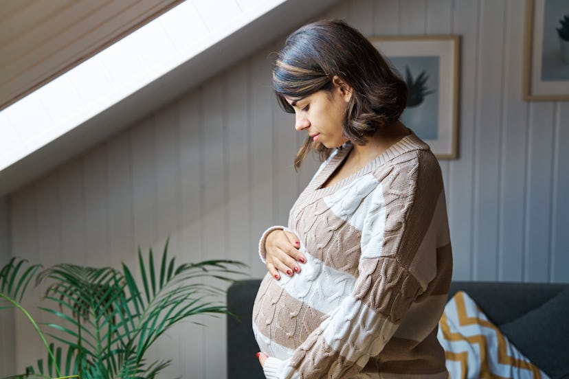 Side view profile of a pregnant woman touching her belly, in a story about placenta previa dos and d...