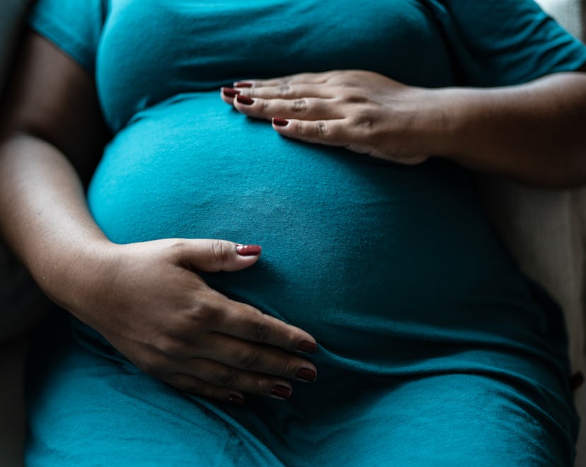 Pregnant woman touching her belly in a story about placenta previa dos and don'ts.