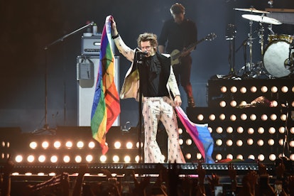 Harry Styles holds rainbow flags as he performs